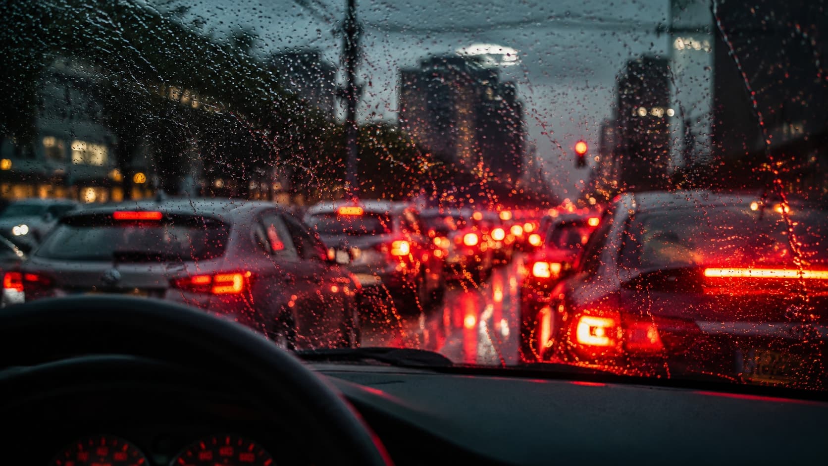 Tráfico de ciudad visto a través de la ventanilla de un coche con lluvia