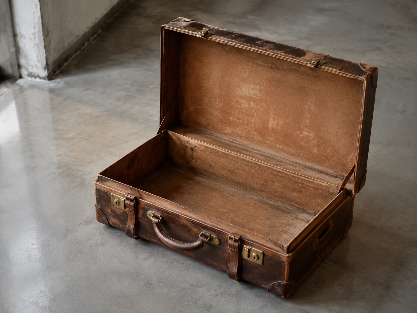 An antique leather suitcase resting open and empty
